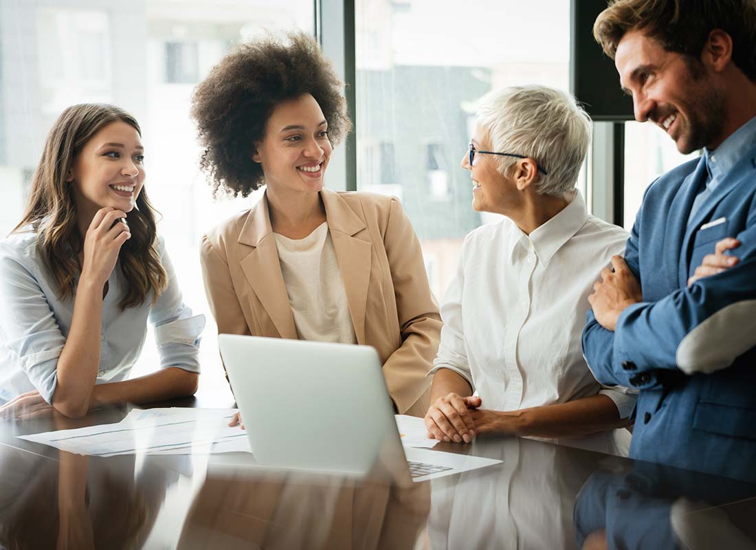 Key Person Life Insurance - Colleagues Laughing and Working Together in the Conference Room of a Modern Office with Lots of Light and Large Pane Glass Windows in the City